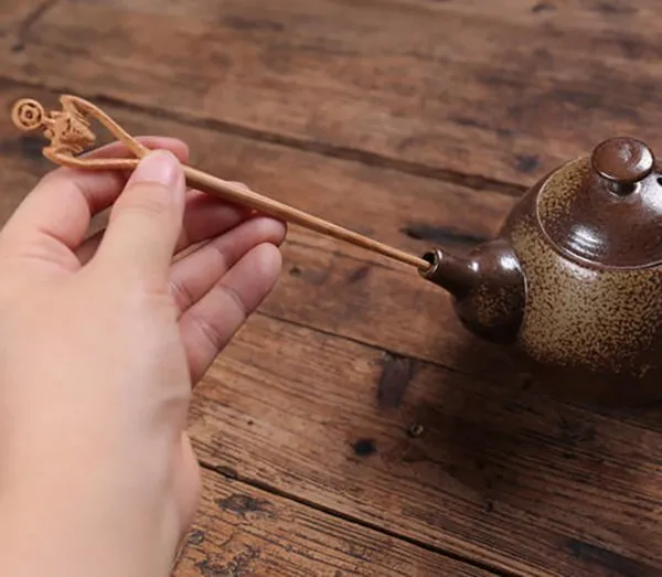 Using a tea needle to unclog the outlet of the teapot